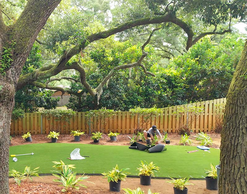 Deep South crew working on an install of an artificial grass back yard with plnats
